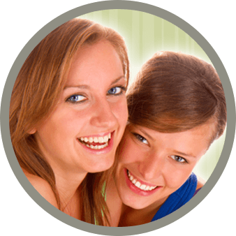 Teo women smiling in front of green backdrop