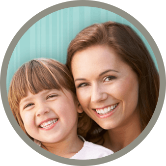 A mother and son smiling together in front of a blue backdrop.