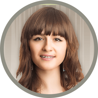 A teenage girl smiling with braces on in front of a tan and white backdrop.