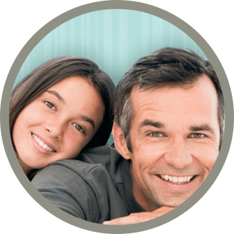 A father and daughter smiling together in front of a blue backdrop.